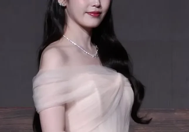 A atriz e cantora IU em retrato de coletiva de imprensa, com vestido claro de tule, em "A Coroa Perfeita"