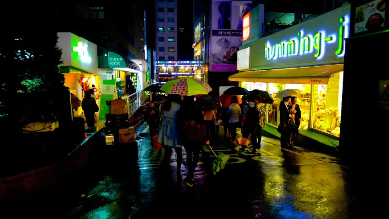 Rua de Seul à noite sob chuva com luzes refletidas no asfalto